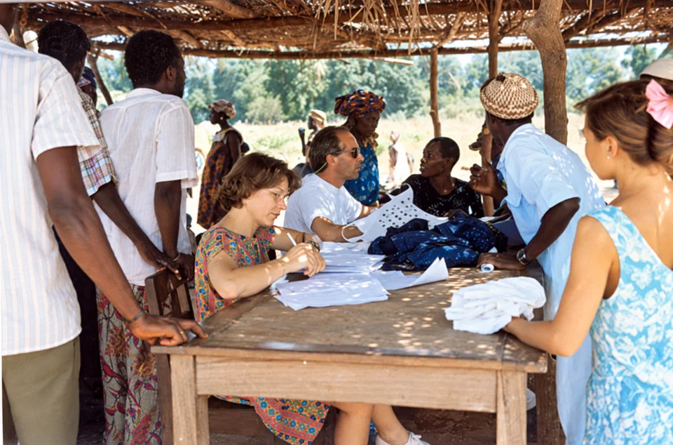 Bénévoles et habitants réunis autour d’une table pendant une mission au Sénégal et au Mali.